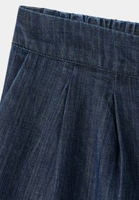 Jupe en denim bleu foncé avec taille élastique et plis cousus sous la taille pour une coupe décontractée.