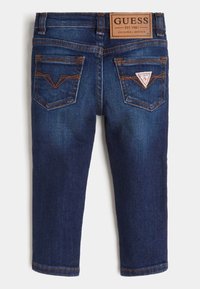Mörk tvättade denimjeans med rak bendesign, som har två bakfickor och en beige märkesetikett vid midjan, med kontrasterande sömmar.