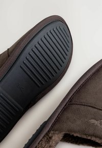 Brune slippers med en struktureret gummisål med en rillemønster, blødt tekstiloverdel og en hyggelig indvendig foring. Størrelse 42 synlig.