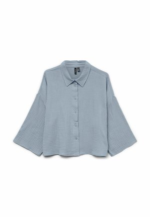Chemise bleu clair texturée, manches longues, boutonnée, avec manches larges et col pointu, affichée à plat sur un fond blanc.