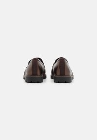 Bruine leren schoenen met een gladde afwerking, voorzien van een contrasterende verticale streep, rubberen zool met een gestructureerd profiel en een lage uitvoering.