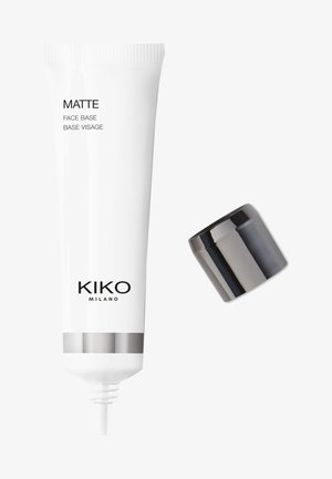 Tube blanche étiquetée "MATTE FACE BASE" avec un texte noir et des accents argentés. Inclut un capuchon noir amovible. Fini lisse et brillant.