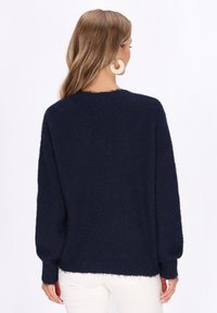 Navyblauer gestrickter Pullover mit einer lockeren Passform, langen Ärmeln und gerippten Bündchen sowie Saum. Weiche Textur mit einem leicht flauschigen Aussehen.