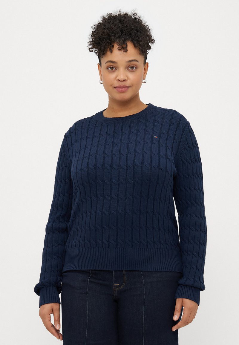 Σκούρο μπλε πλεκτό πουλόβερ με υφή καλωδίου, ριμπ μανσέτες και στρίφωμα. Διαθέτει ένα μικρό λογότυπο στο στήθος.