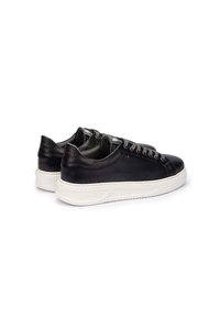 Zapatillas de cuero negro con suelas de goma blanca, que presentan cordones redondos, costuras sutiles y un diseño minimalista. Logo grabado en el talón.