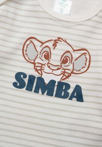 Close-up of a beige and white striped baby onesie with a cartoon Simba face and "SIMBA" text in dark blue on the front.