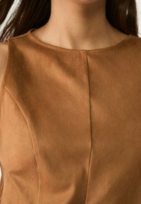 Brązowy zamszowy top bez rękawów z okrągłym dekoltem, charakteryzujący się gładką teksturą i subtelnym wykończeniem szwów z przodu.