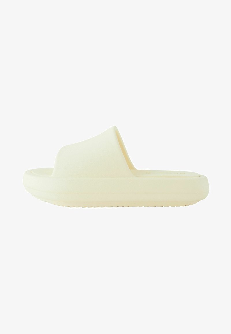 Cremefarvet slidesandal med en enkelt bred strop, flad sål og tekstureret overflade. Letvægtsdesign, rund tå og diskret branding.