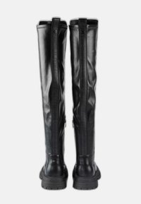 Botas altas de cuero negro con suelas gruesas, cremallera trasera y una franja vertical con marca que recorre la parte trasera de cada bota.