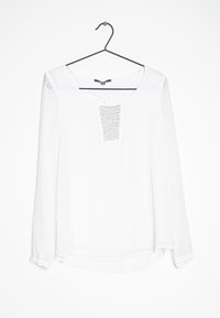 Hvid langærmet bluse med en rund halsudskæring og en dekorativ, struktureret panel foran. Stoffet ser glat og letvægtigt ud.