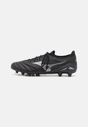 Schwarzer Fußballschuh mit silbernem Logo, geschnürten Schnürsenkeln und geformten Nocken an der Sohle, von der Außenseite auf weißem Hintergrund gezeigt.