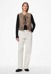 Prsluk s leopard uzorkom s vezanjem sprijeda, složen preko crne majice s dugim rukavima. Uparen s bijelim širokim hlačama i crnim čizmama na deblju petu.