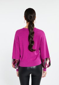 Maglione magenta con maniche a palloncino testurizzate, caratterizzato da paillettes multicolori in motivi a onde, bordo a coste e silhouette aderente.