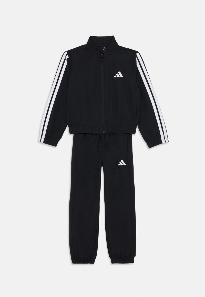 Tuta nera realizzata in tessuto liscio, con strisce bianche lungo le maniche e le gambe, giacca con zip e pantaloni con cintura elastica.