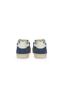 Sneakers in suede blu navy con suole beige, dotati di colli in pelle bianca imbottiti e design a bassa altezza. Stile classico con lacci.
