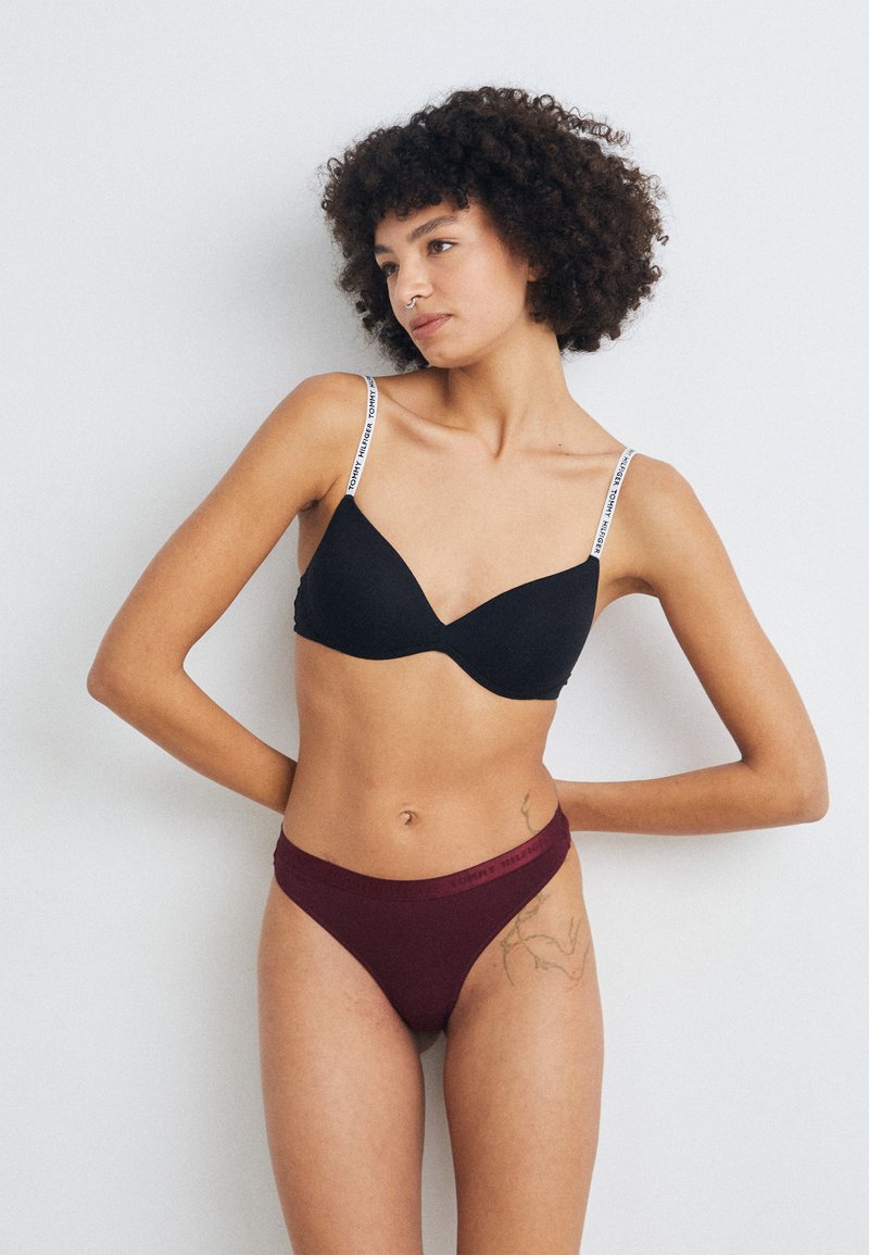 Black bra with adjustable straps featuring logo print; paired with maroon high-cut panties, smooth fabric and elastic waistband.