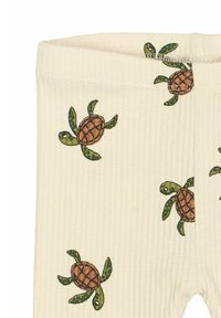 Krém színű, zöld és barna teknősbékákkal díszített mintás pamut leggings. Bordázott textúrával és puha, rugalmas derékpánttal rendelkezik.