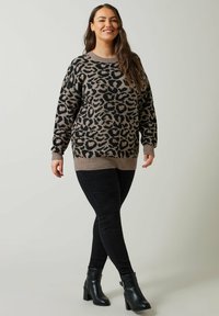 Leopardenmuster Pullover in Hellbraun und Schwarz, gestrickte Textur, Rundhalsausschnitt, gerippte Bündchen und Saum, kombiniert mit schwarzen Skinny-Jeans und Stiefeletten.