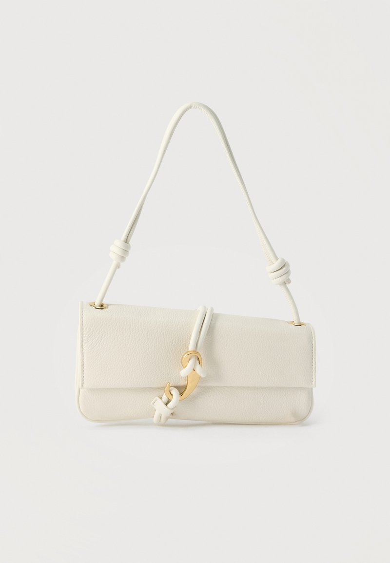 Εκρού δερμάτινη τσάντα ώμου με καμπυλωτό χρυσαφένιο κούμπωμα και ρυθμιζόμενο λουρί με κόμπους σε απλό φόντο.