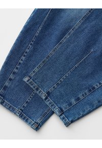 Nahaufnahme von zwei blauen Jeansbeinen mit sichtbaren Nähten und Saumstichen auf weißem Hintergrund.