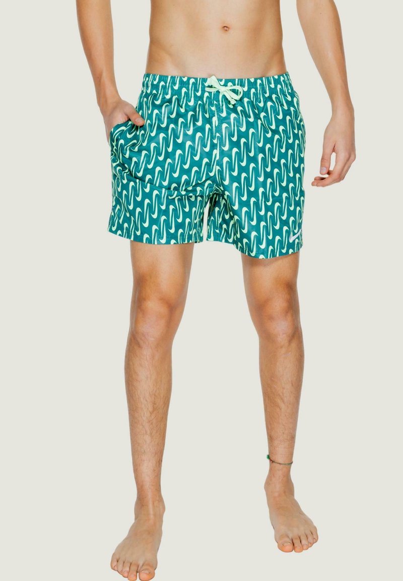 Costume da bagno verde con motivo a onde bianche, vita elastica, chiusura con cordino e tasche laterali. Tessuto sintetico liscio.
