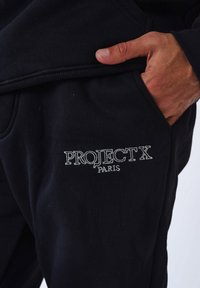 Pantalones de chándal negros con logo bordado "PROJECT X PARIS". Fabricado en una suave mezcla de algodón con una textura lisa, bolsillos laterales y cinturilla elástica.
