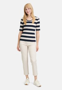 Navy and cream striped short-sleeve top with a round neck, paired with beige cropped pants and light sneakers. Smooth texture.