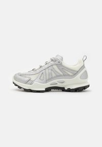 Sneaker med et grått og hvitt mesh-overdel med gummierte detaljer, teksturert såle og integrert snøresystem for en sikker passform.