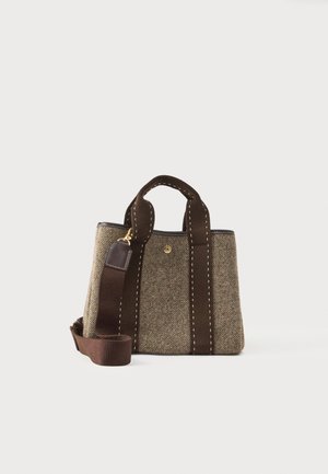 Kleine strukturierte Handtasche aus beige-braunem Tweed mit dunkelbraunen Griffen und abnehmbarem Schultergurt auf hellen Hintergrund.