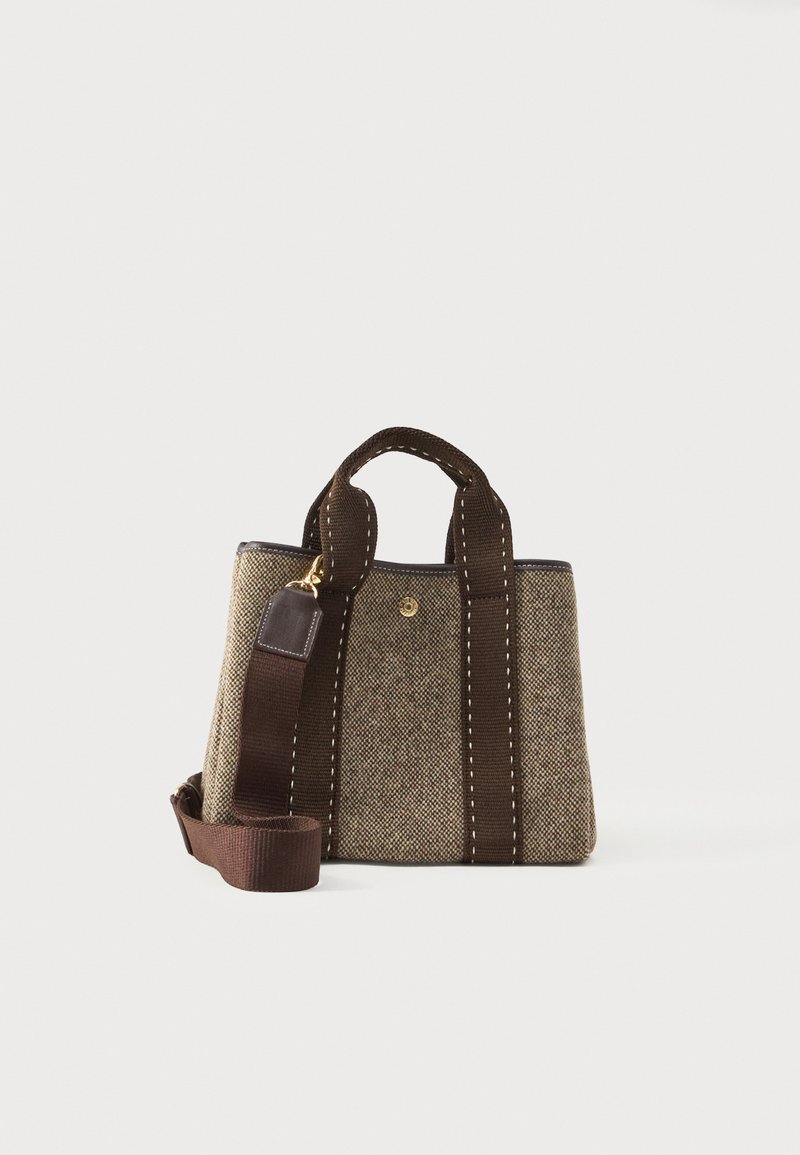 Μικρή δομημένη μπεζ και καφέ τσάντα από τουίντ με σκούρους καφέ λαβές και αποσπώμενο λουρί ώμου σε ανοιχτό φόντο.