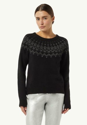 Schwarzer Pullover mit Rundhalsausschnitt, der aufwändige silberne Stickerei entlang der Passe aufweist. Glattes Material und lange Ärmel. Kombiniert mit glänzenden silbernen Hosen.