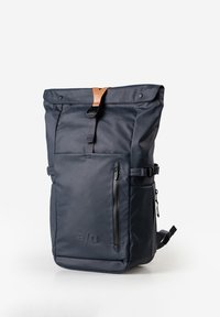 Eleganter dunkelblauer Rolltop-Rucksack mit vorderer Reißverschlusstasche, verstellbaren Seitenriemen und Details aus braunem Leder an der Schnalle vor weißem Hintergrund.