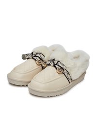 Pantofole beige trapuntate senza lacci con morbida fodera in pelliccia bianca e una fascia decorativa con motivo in bianco e nero che presenta accenti dorati.