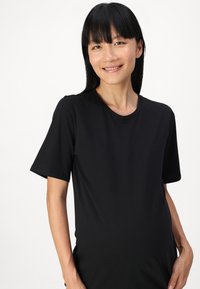 T-shirt nera a maniche corte con scollatura rotonda, realizzata in tessuto morbido, design attillato, caratterizzata da una texture liscia e senza motivi visibili.