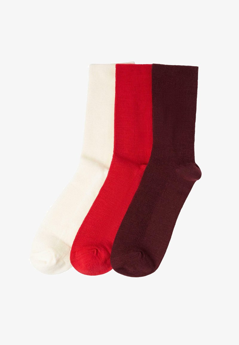 Drie paar geribbelde sokken in wit, rood en donkermaroon, gemaakt van een zachte stof met versterkte tenen.