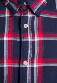 Marineblaue karierte Flanellhemd mit rot-weißer Karomuster. Mit einem Button-Down-Kragen und hellen Knöpfen ausgestattet.