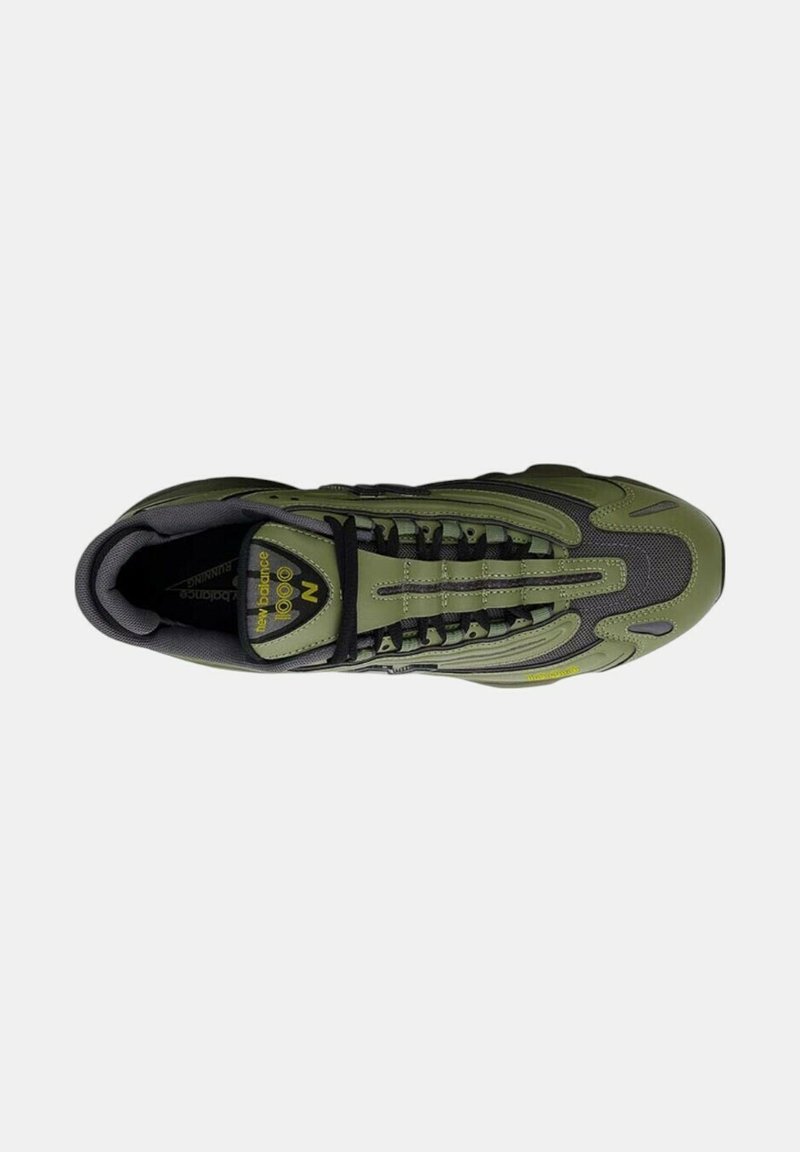 Chaussure de sport verte et noire avec un mesh texturé, un système de laçage et des accents réfléchissants. Présente un branding proéminent sur la languette.