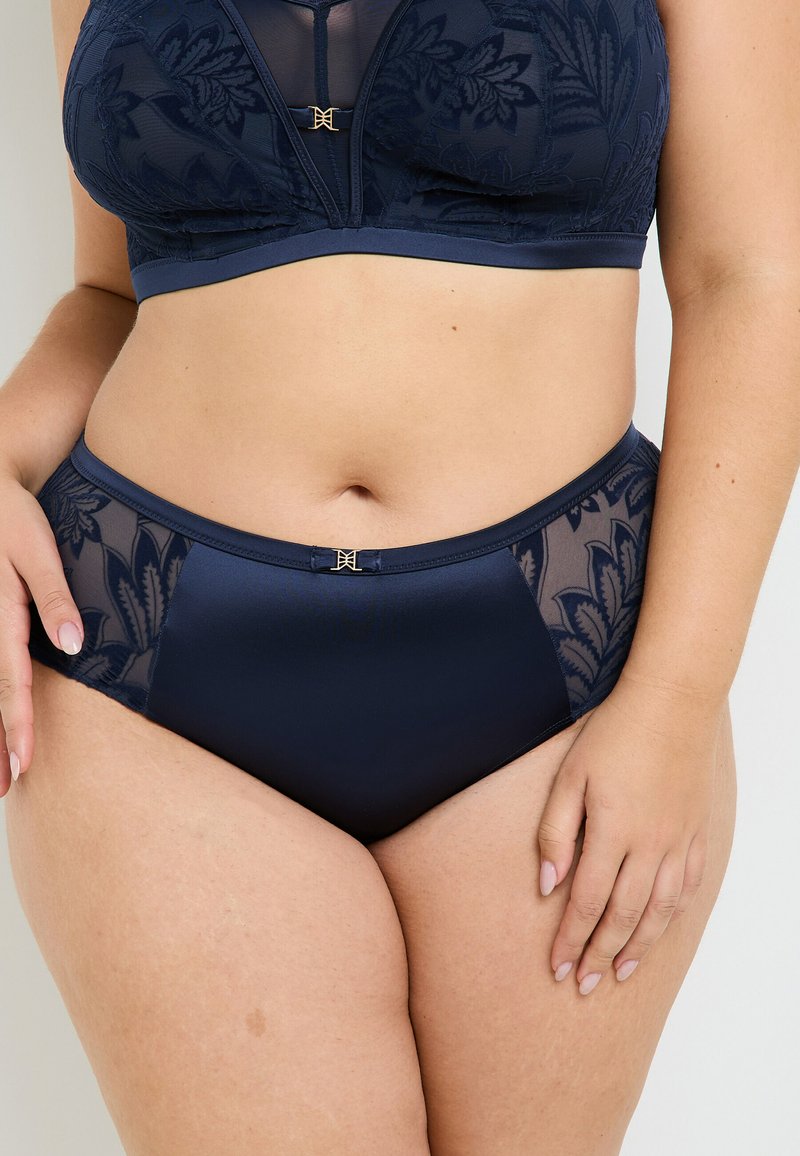 Set di lingerie blu navy composto da un bralette in rete con ricami floreali e pantaloni alti coordinati, arricchito da dettagli in metallo dorato.