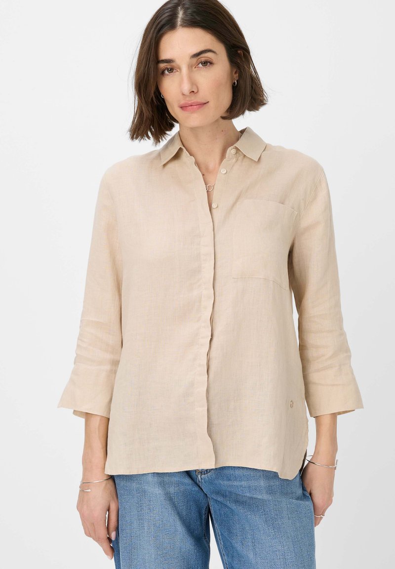 Beige linen button-up shirt with long sleeves, chest pocket, and a relaxed fit. Collar and cuffs have a subtle texture.
