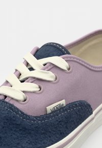 Vans shoes feature a mix of purple and navy suede materials, white laces, and a textured navy accent with a logo tag.