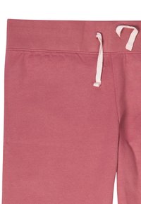 Pantaloni jogger in cotone rosa con una texture morbida, dotati di una vita elastica e lacci. Design semplice, senza ulteriori motivi o accenti.