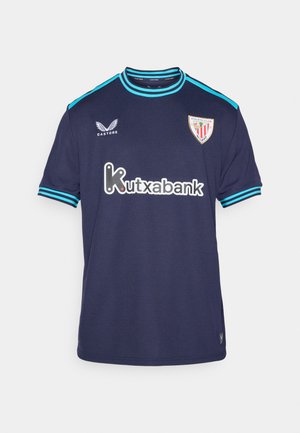 Tummansininen Athletic Club Bilbao -jalkapallo-asu turkoosilla korostuksella, Castore-logo ja Kutxabank-sponsorin logo edessä.