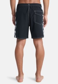 Svart svømmeshorts med rutete mønster på sidene, elastisk midje, hvite sømmer og en baklomme.