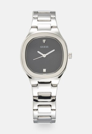 Montre en acier inoxydable argenté avec un boîtier rectangulaire, un cadran noir, des aiguilles argentées et un petit accent en diamant à la position de 12 heures.