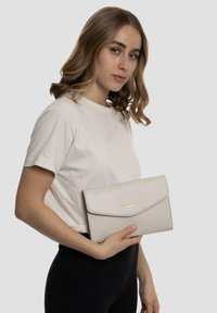 Heller grauer, strukturierter Clutch aus Leder mit einem Klappenverschluss und einem dezenten goldenen Logo. Glatte Oberfläche und rechteckige Form.