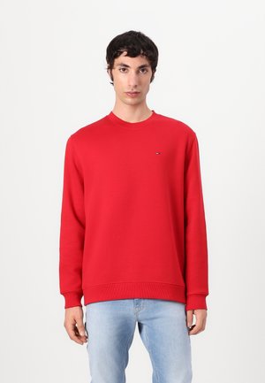 Sweat-shirt rouge, col rond, manches longues, en matière mélange de coton, avec des poignets et un ourlet élastiques, petit logo sur la poitrine gauche, associé à un jean bleu clair.