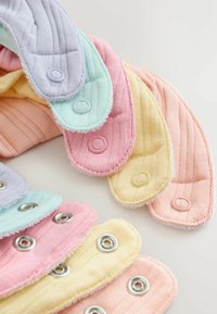 Pile de serviettes hygiéniques réutilisables en tissu aux couleurs pastel avec boutons-pression sur une surface claire.
