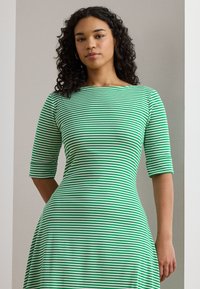 Green and white striped dress with three-quarter sleeves, fitted bodice, and flared skirt, made of a soft, smooth fabric.