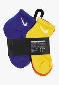 Négy pár pamut zokni lila, kék, sárga és narancssárga színben, bordázott mandzsettával és fehér Nike logóval. Csomagolva méretinformációval.