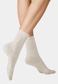 Helle beige Knöchelsocken mit gerippten Bündchen, die ein diagonales Texturmuster und eine glatte Oberfläche aufweisen, entworfen für Komfort und Atmungsaktivität.